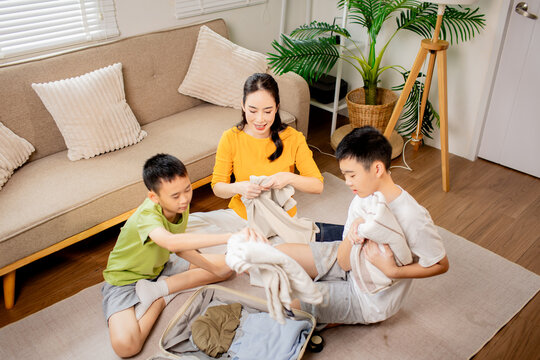 Family Packing Clothes Together in a Suitcase for Vacation