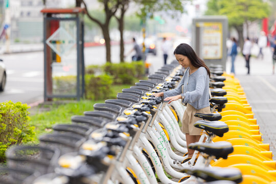Woman renting public bicycle at station in city