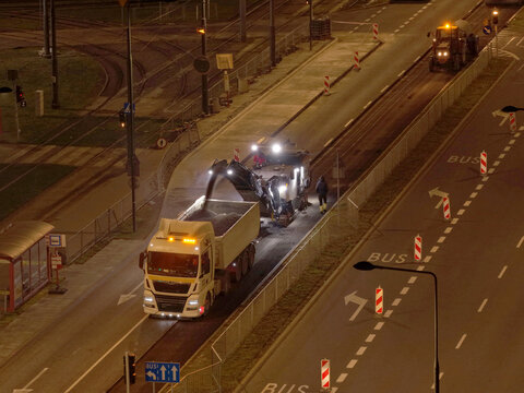 Nighttime road construction and asphalt resurfacing with heavy machinery