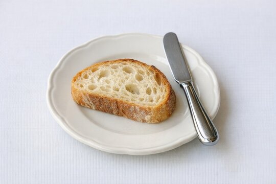 A slice of bread served with a sharp knife on a plate, perfect for everyday use or a quick snack