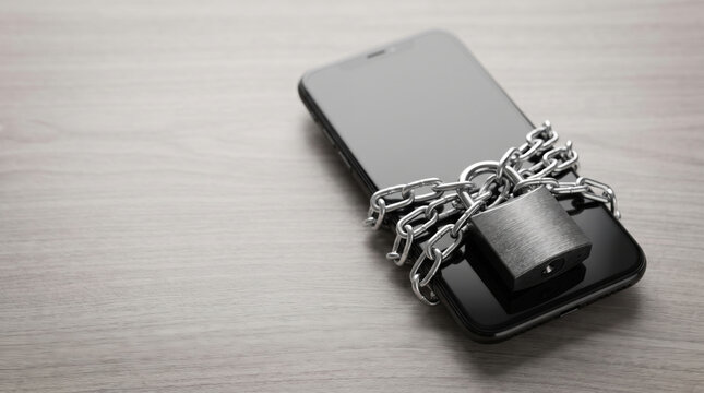 Digital smartphone locked with chain and padlock suggesting detox and privacy. Mobile phone social media addiction problem. disconnect offline balance relaxation, mental control privacy