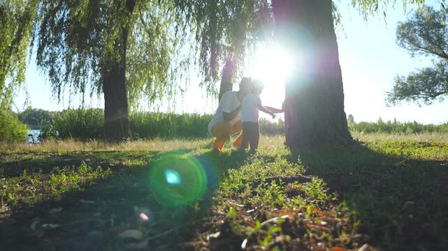 Young dad and his little child finding nest hole in trunk of tree at sunny summer day. Happy family spending time together at nature. Sunlight at background. Low angle view Slow motion
