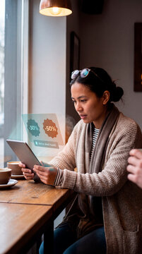 Attentive woman discovering better deal alert on augmented reality shopping hologram at cafe