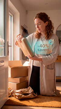 Pleased woman unwrapping package as augmented reality savings confirmation hologram glows