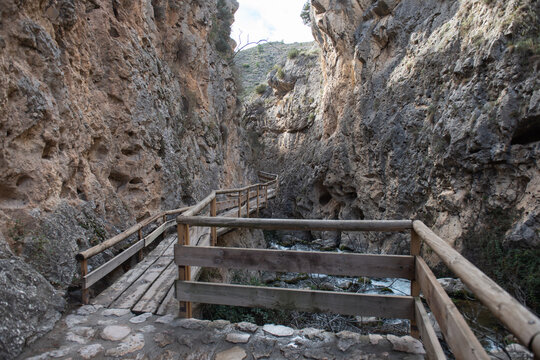 Wooden walkway through rocky canyon with flowing river below