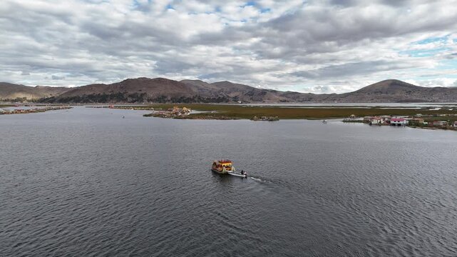 Beautiful drone video following a traditional reed boat navigating Lake Titicaca surrounded by the vast Andean landscape.