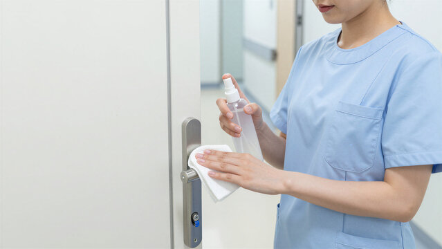 Japanese Nurse Disinfecting Clinic Door Handle, Copy space on the left