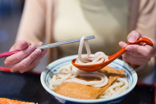 Enjoying delicious udon noodles with spoon and chopsticks
