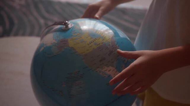 Child studying world map on globe pointing finger at Canada country