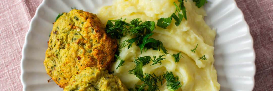 A plate holds mashed potatoes topped with finely chopped herbs beside turkey meatballs, creating a nutritious meal option for breakfast or lunch at home, banner