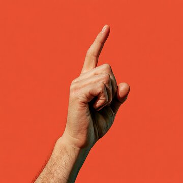A human hand with index finger extended upwards against an orange backdrop