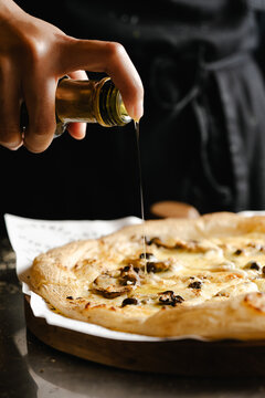 Pouring Olive Oil over Fresh Baked Pizza in Restaurant Kitchen