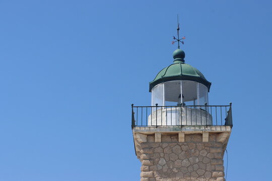 Scenic views of Melagavi Lighthouse and the rugged coastline of Perachora Peninsula, Greece, featuring rocky cliffs, clear waters, boats, and the beautiful Corinthian Gulf.