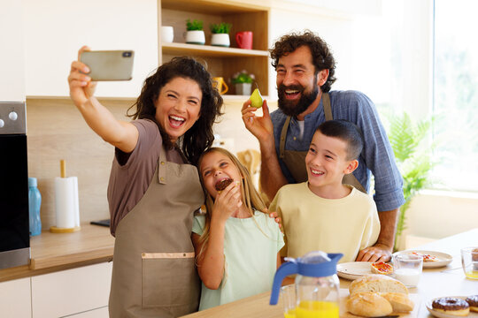 Happy family taking a selfie together while enjoying breakfast at home