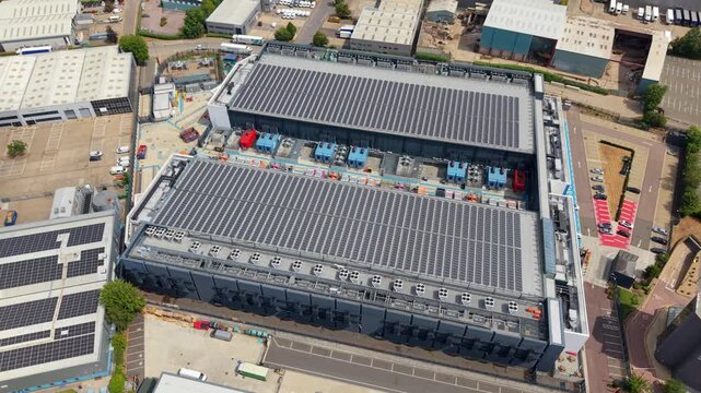 Aerial view of NTT 3 Data Center featuring large rooftop solar panel arrays and industrial cooling units, situated within a commercial business park in Hemel Hempstead, England, United Kingdom.