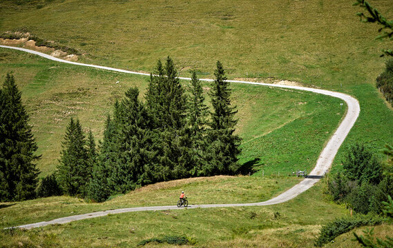 Attractive senior woman riding an electric bicycle on a mountain biking tour through sunny alpine meadows and scenic mountain landscapes above Balderschwang, Allg&auml;u Alps, Bavaria, Germany.