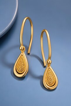 Elegant Gold Teardrop Earrings with Textured Surface on Blue Background Close-Up Product Photography