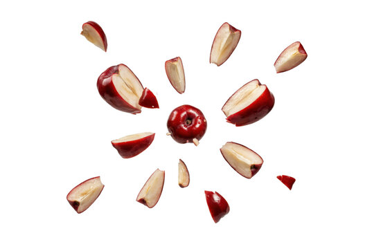 Red apple fruit exploding into various slices and pieces on a white surface isolated on a transparent background