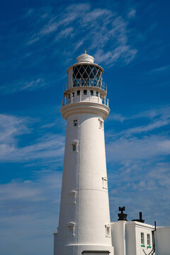 Close-up view of the historic Flamborough Head Lighthouse on the East Yorkshire coast of England, with its distinctive white tower and lantern room standing against a deep blue summer sky.