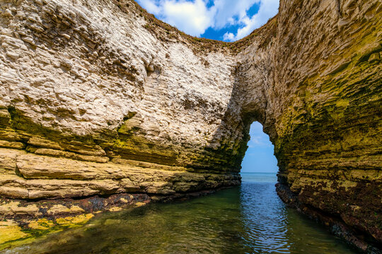 Natural sea arch and dramatic chalk cliffs at Flamborough Head on the Yorkshire coast of England. The view through the eroded rock formation opens towards the North Sea.