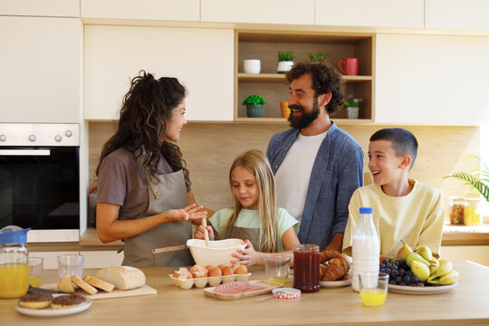 Happy family cooking and preparing homemade breakfast together at home