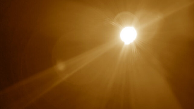 abstract photo of light burst among trees and glitter bokeh. image is blurred. yellow golden bokeh pattern background. Real optical lens flare on black backdrop. sunrays, sun rays beam, burst, sunbeam