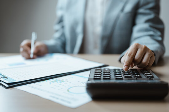 An accountant performs a financial audit by reviewing a budget report and document beside a calculator, combining analysis, planning, expense and revenue checks to strengthen financial control.