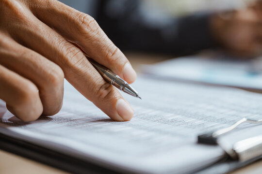 An accountant traces figures on a report while making a comparison of a budget against actual expense, using financial analysis, review, variance data and planning to refine the next business budget.