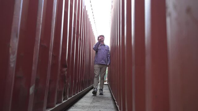One female logistics worker uses a two way radio and hand signals to direct cargo operations at a shipping container yard. Concept of logistics, freight transport, communication, and supply chain.