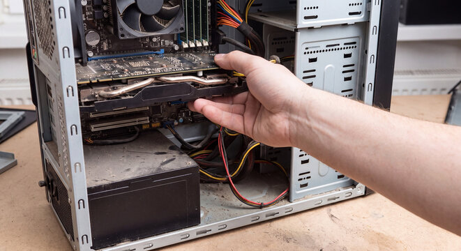 Male hand examining internal components and graphics card inside open desktop personal computer case during technical diagnostic check