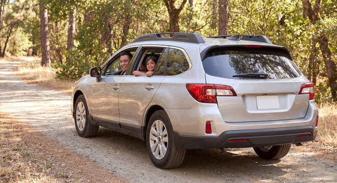 Silver SUV car driving along scenic dirt road in forest with family enjoying travel vacation journey and outdoor summer adventure in nature