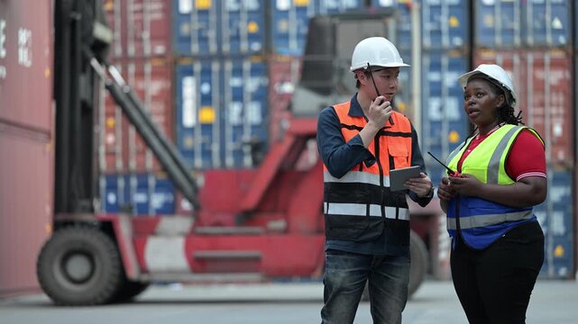 Logistics workers review operational data while inspecting shipping containers at a cargo yard. Concept of supply chain, freight transport, warehouse operations, teamwork, and logistics management.