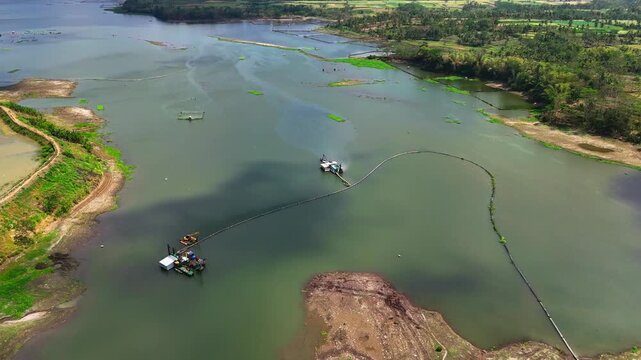 Aerial view of suction dredges and floating platforms operating on the Sengguruh reservoir to remove sediment and debris in Malang, East Java, Indonesia.