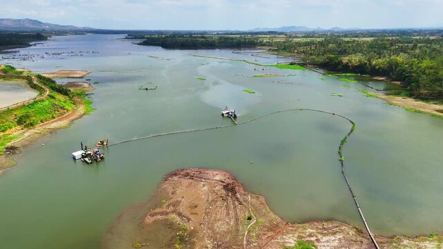 Aerial view of specialized suction dredges and floating platforms extracting sediment and debris from the Sengguruh reservoir bed in Malang, East Java, Indonesia.