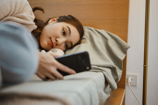 A woman stares at a smartphone while lying awake in bed as social media, screen time and addiction increase stress, loneliness and pressure, revealing how mental health can suffer from social use.
