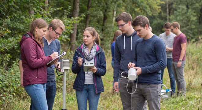 A team of young geology and biology students uses electronic measurement sensors and testing instruments during outdoor environmental field work