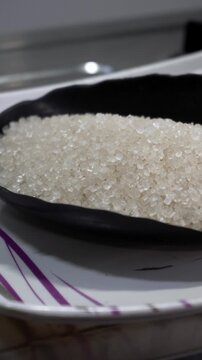 Macro close-up shot of white granulated sugar crystals in a bowl
