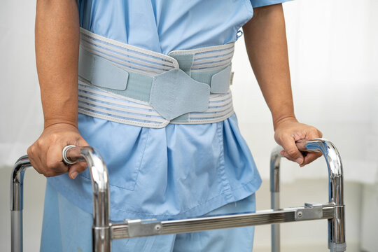 Asian lady patient wearing back pain support belt for orthopedic lumbar with walker.