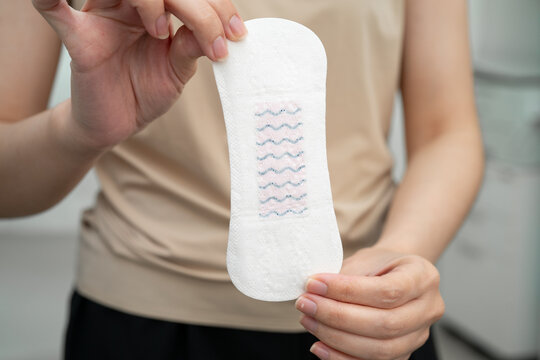 Asian woman holding sanitary napkin pad for hygiene menstrual period cycle protection.