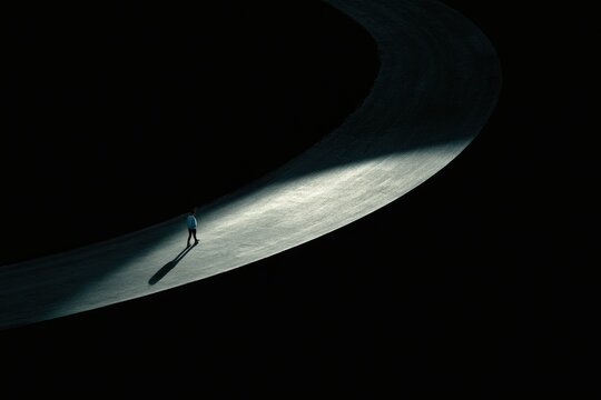 Lone figure walks a glowing path through deep darkness