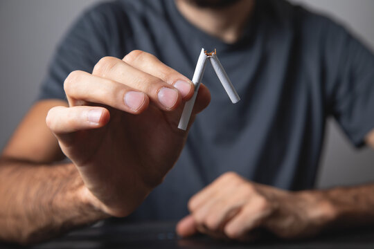 Caucasian man breaking cigarette. No smoking