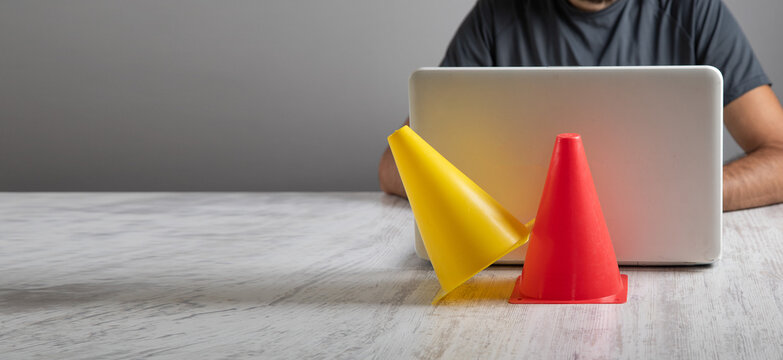 Man using computer with a traffic cone.