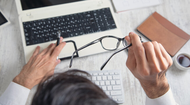 Businessman showing eyeglasses while working in computer.