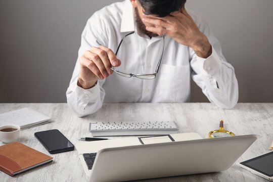 Businessman showing eyeglasses while working in computer.