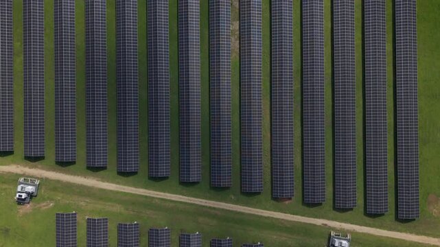 Aerial view of rows of solar panels installed on green grass fields in The Basin, Victoria, Australia.