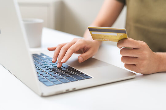 Close up of woman hand holding credit card and typing on a laptop computer keyboard for online shopping payment, secure digital banking and e-commerce retail transaction concept.