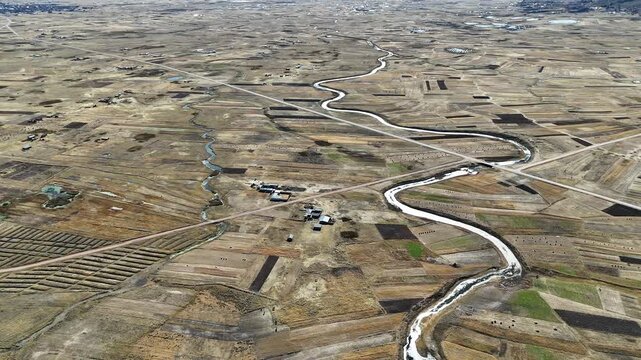 Cinematic aerial footage of a meandering river flowing through the vast high-altitude Andean Altiplano in Peru.