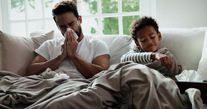 Sick, father and child in home with blowing nose, influenza or cold congestion in allergy season. Wellness, dad and son on sofa with paper napkin, family flu or viral infection with household risk.