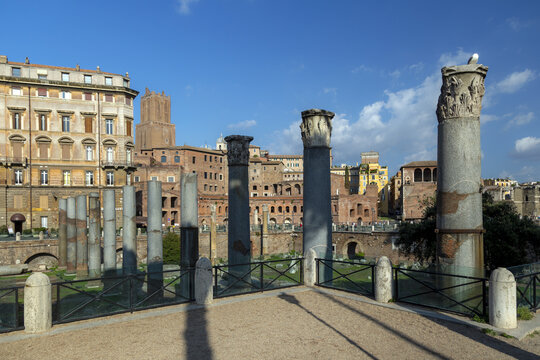 View of the ancient Roman columns of the Forum of Trajan with historic buildings and clear blue sky in the background Rome, Lazio, Italy.