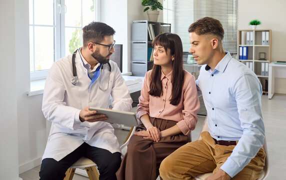 Couple and doctor consultation in clinic, fertility planning. Specialist explains options on a tablet, guiding couple on tests and next steps. Clear concept of family planning consultation.